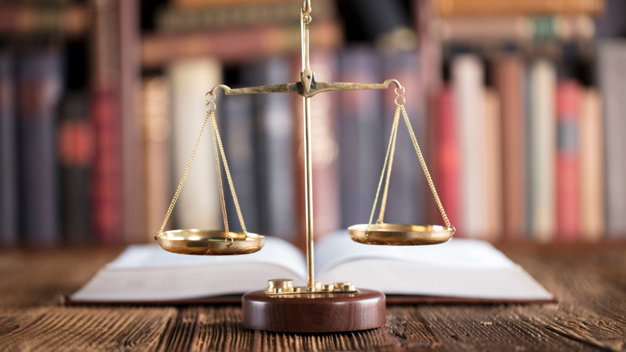 Scales of Justice in front of books, symbolic of our timeshare cancellation services near Kansas City, MO.